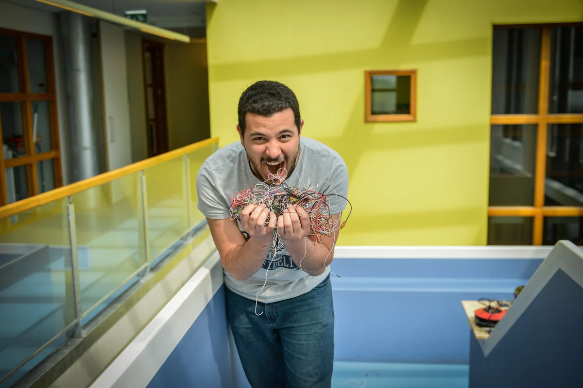 Een man met een bundel gekleurde draden in een gele binnenruimte